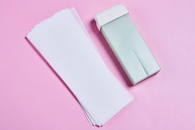 Bande de cire et cartouche de cire sur fond rose pour l'épilation